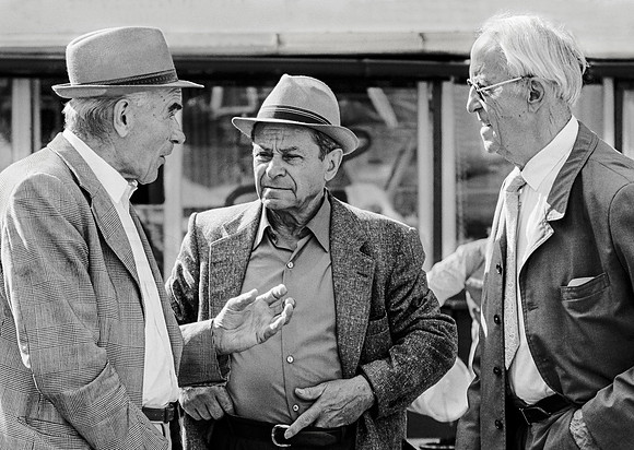 " three men in conversation in the street"